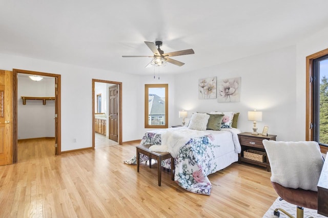 bedroom featuring a spacious closet, ceiling fan, baseboards, and light wood-style floors