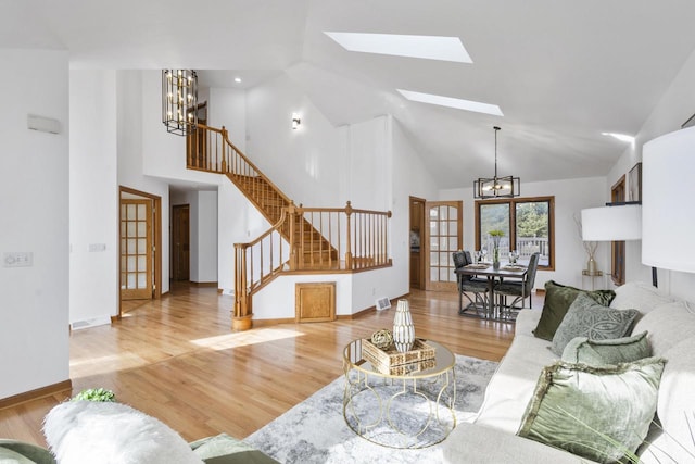 living area featuring a notable chandelier, stairway, high vaulted ceiling, and wood finished floors