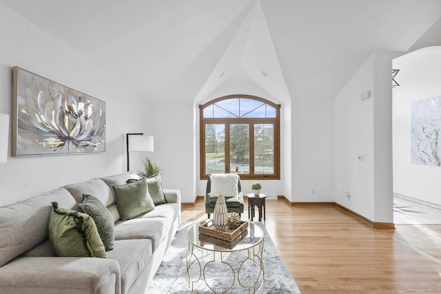 living area with baseboards, lofted ceiling, and light wood-style floors