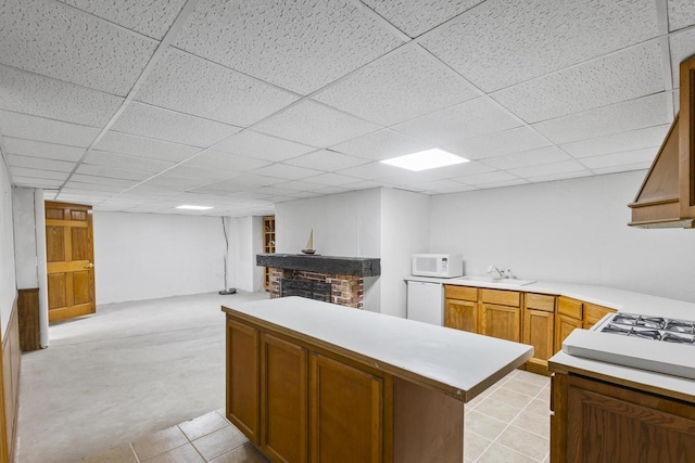 kitchen featuring white appliances, a sink, light countertops, a brick fireplace, and open floor plan