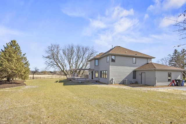 back of house featuring a lawn, a deck, and a shingled roof