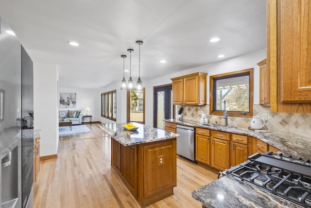 kitchen featuring dishwasher, light stone counters, a center island, and a sink