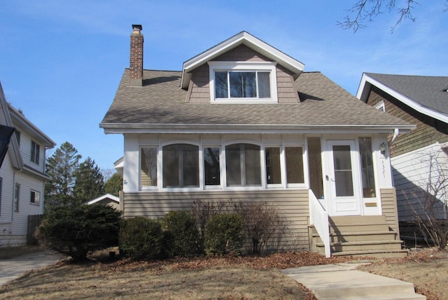 bungalow-style home featuring roof with shingles, a chimney, and entry steps