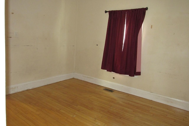 unfurnished room with visible vents, baseboards, and wood-type flooring