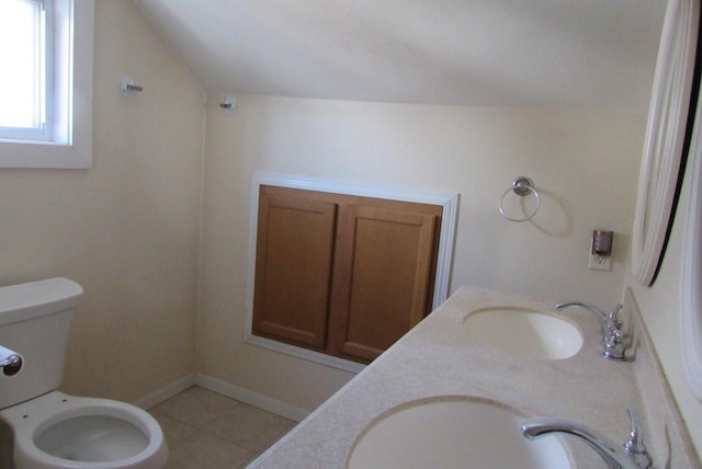 full bath with double vanity, vaulted ceiling, toilet, and a sink