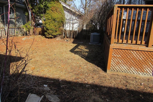 view of yard with a deck, central air condition unit, and fence