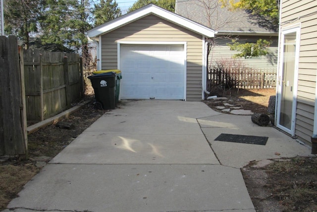 garage featuring concrete driveway and fence