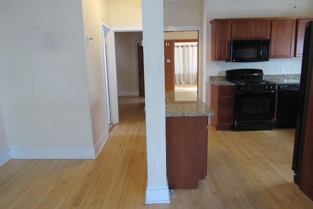 kitchen with light stone countertops, baseboards, light wood-style flooring, black appliances, and brown cabinets