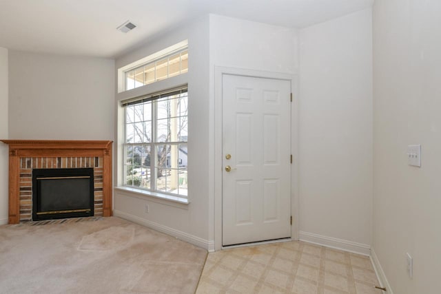 foyer entrance with tile patterned floors, visible vents, baseboards, and a brick fireplace