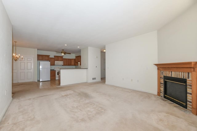 unfurnished living room with visible vents, ceiling fan with notable chandelier, a brick fireplace, and baseboards