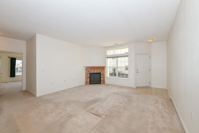 unfurnished living room featuring a fireplace, a healthy amount of sunlight, light colored carpet, and baseboards