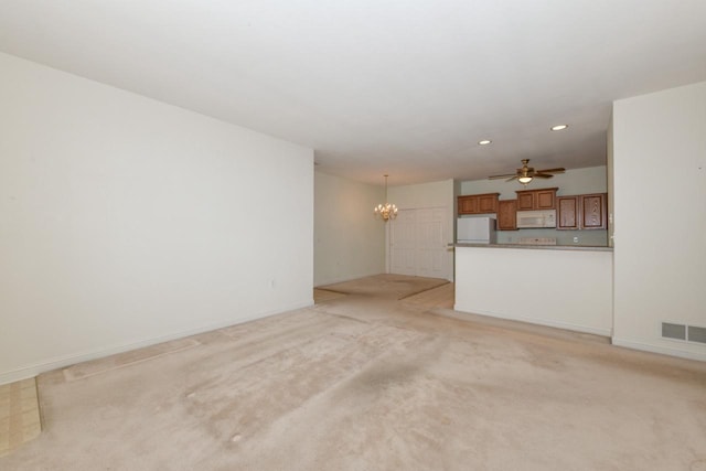 unfurnished living room with visible vents, baseboards, light carpet, ceiling fan with notable chandelier, and recessed lighting