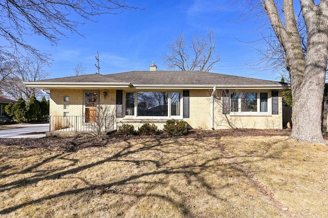 ranch-style home featuring brick siding, covered porch, and a chimney