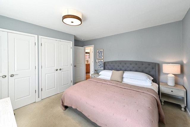 bedroom featuring light colored carpet and two closets