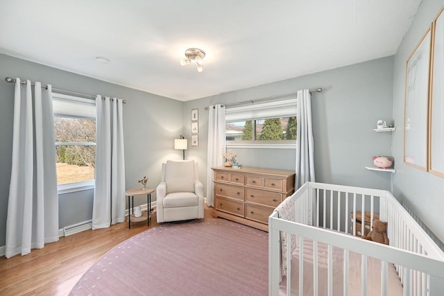 bedroom featuring a nursery area, wood finished floors, and baseboards