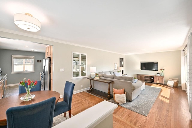 living area with light wood-style flooring, crown molding, and baseboards