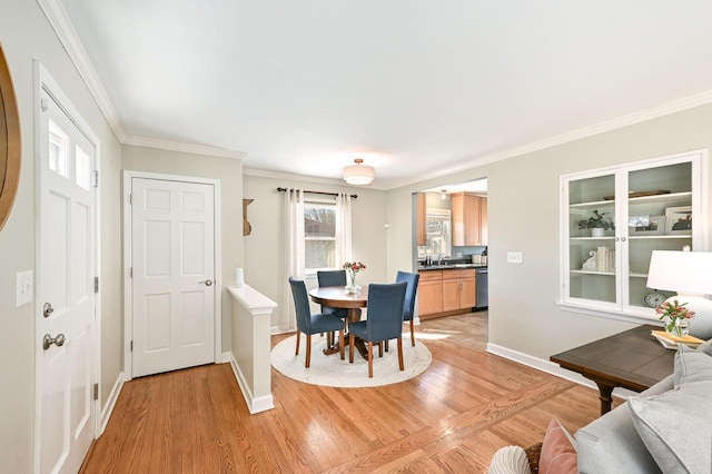 dining room featuring baseboards, light wood-style floors, and ornamental molding