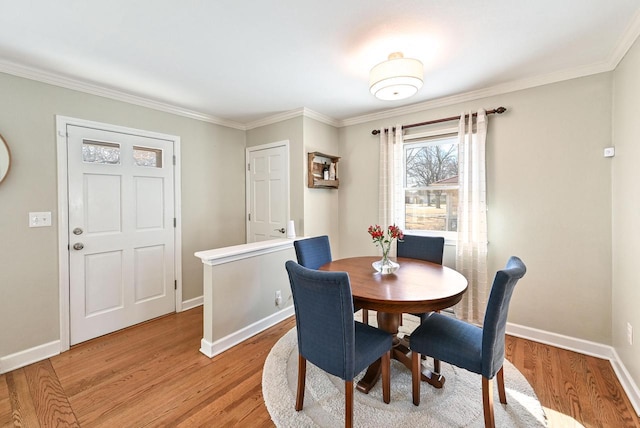 dining space with light wood-type flooring, baseboards, and crown molding