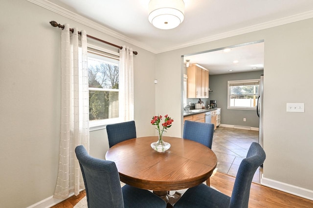 dining space with crown molding, baseboards, and light wood finished floors