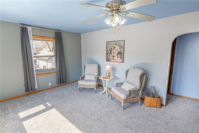 sitting room with baseboards, carpet floors, arched walkways, and a ceiling fan