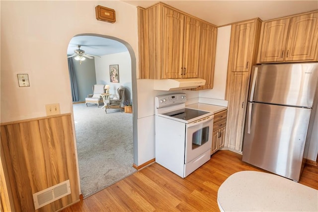 kitchen featuring visible vents, freestanding refrigerator, under cabinet range hood, light carpet, and white range with electric stovetop