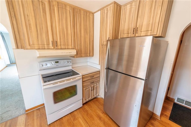 kitchen with visible vents, white electric range, freestanding refrigerator, arched walkways, and exhaust hood