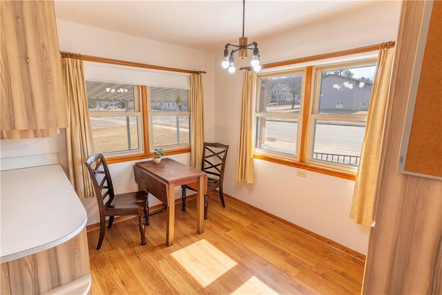 dining space featuring a notable chandelier, baseboards, and light wood finished floors