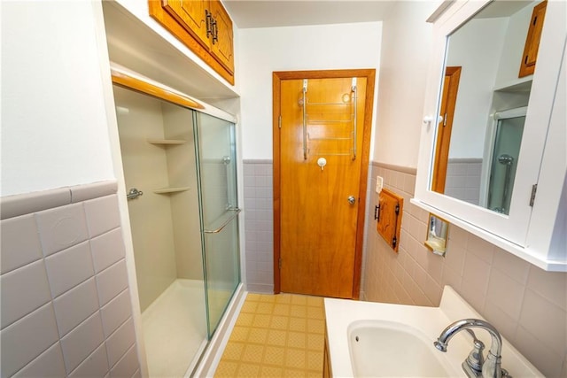 full bathroom featuring tile patterned floors, tile walls, wainscoting, and a shower stall