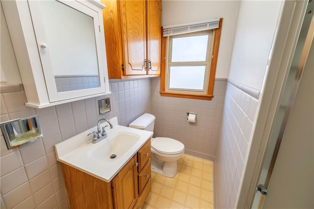 bathroom with tile patterned floors, toilet, vanity, and tile walls