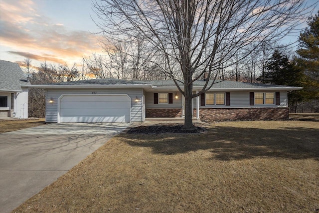 ranch-style home featuring driveway, a yard, an attached garage, brick siding, and a chimney