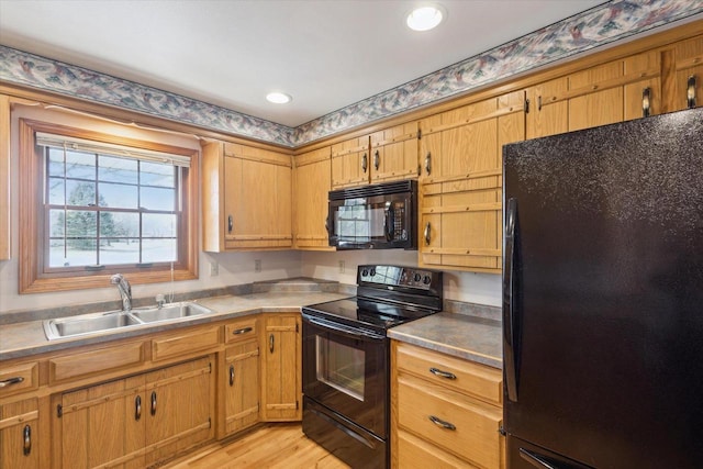 kitchen with a sink, light wood-style floors, black appliances, and recessed lighting