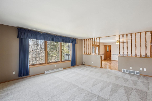 carpeted empty room featuring baseboards, visible vents, baseboard heating, and ceiling fan