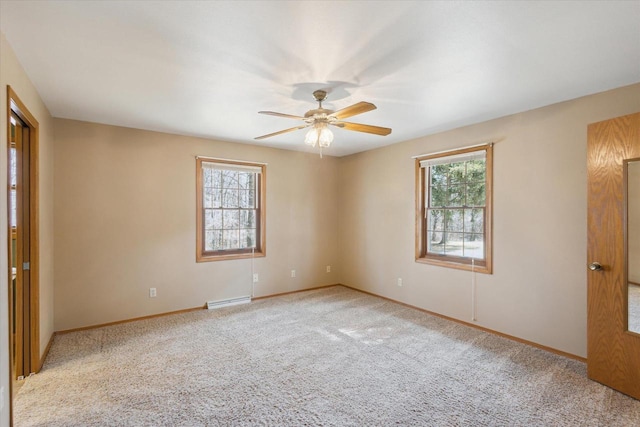 empty room featuring a ceiling fan, carpet, baseboards, and a wealth of natural light