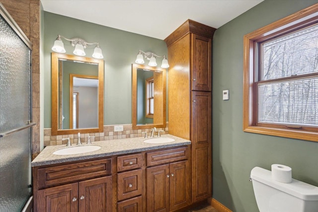 full bath featuring a sink, toilet, a stall shower, and double vanity