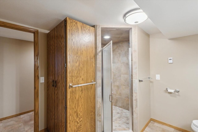 full bathroom with baseboards, toilet, and a stall shower