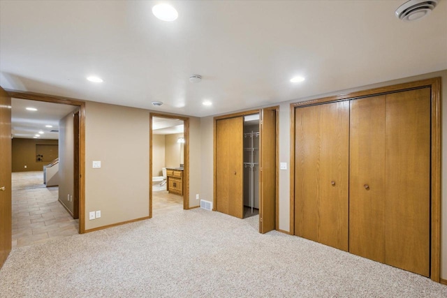 unfurnished bedroom with baseboards, visible vents, recessed lighting, multiple closets, and light carpet