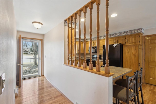 hallway featuring stairs, baseboards, and light wood finished floors