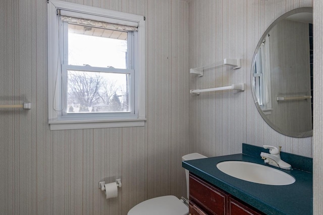 bathroom with wallpapered walls, toilet, and vanity