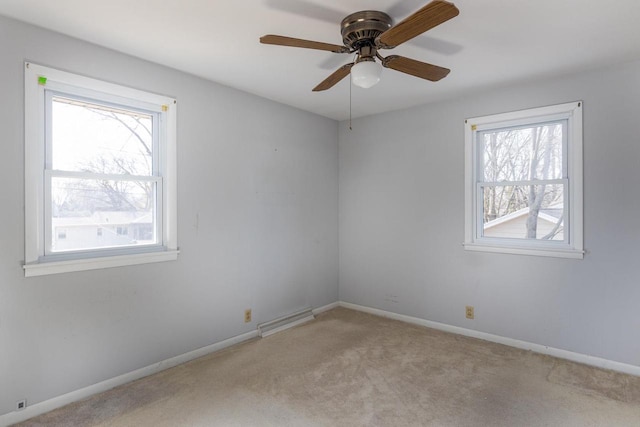 carpeted spare room with visible vents, a healthy amount of sunlight, a ceiling fan, and baseboards