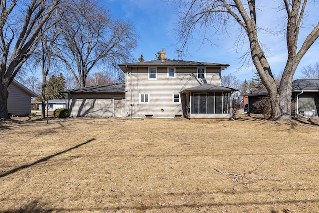 back of property with a chimney, a yard, and a sunroom