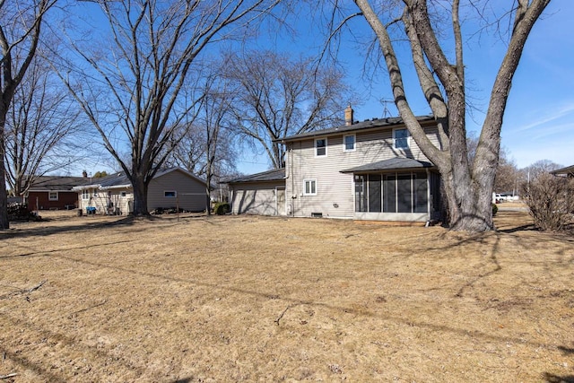 rear view of house featuring a chimney, a yard, and a sunroom