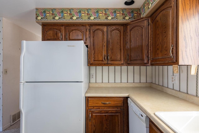 kitchen with visible vents, a sink, backsplash, white appliances, and light countertops