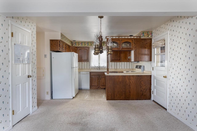 kitchen with wallpapered walls, light countertops, a peninsula, white appliances, and a sink