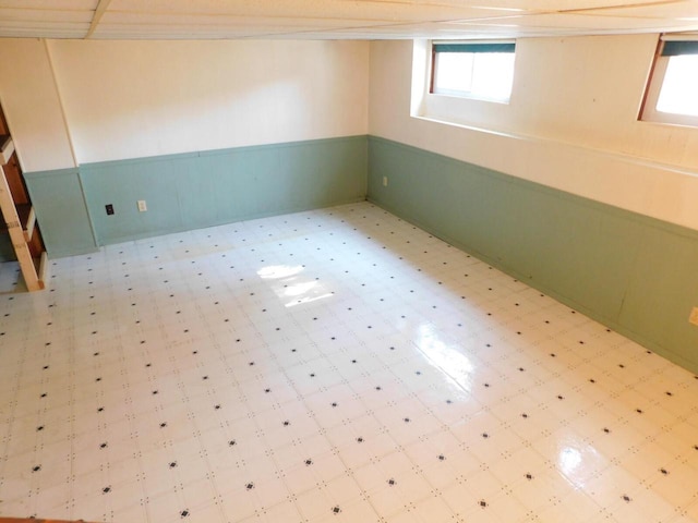 below grade area with tile patterned floors and a wainscoted wall