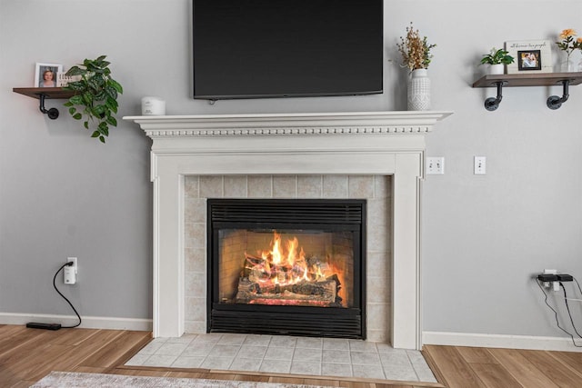 room details with baseboards, wood finished floors, and a tiled fireplace