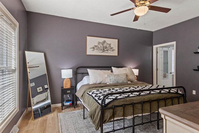 bedroom with visible vents, baseboards, wood finished floors, and a ceiling fan