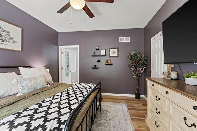 bedroom featuring light wood finished floors, visible vents, a ceiling fan, and baseboards