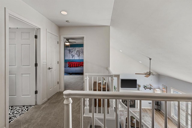 corridor featuring an upstairs landing, lofted ceiling, and carpet floors