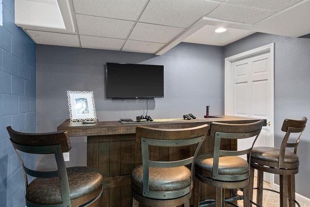 bar featuring recessed lighting, a paneled ceiling, and concrete block wall