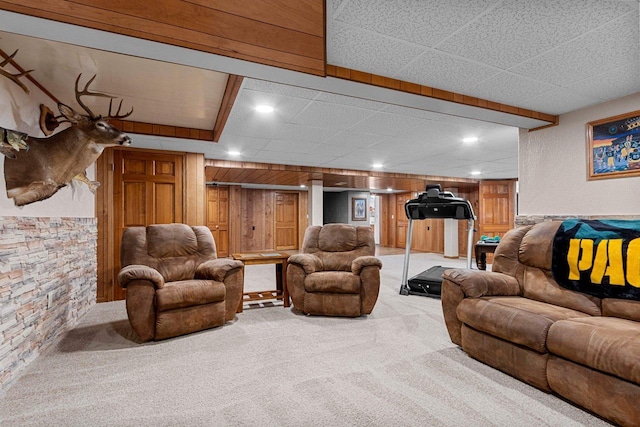 carpeted living area featuring wooden walls, recessed lighting, and a drop ceiling